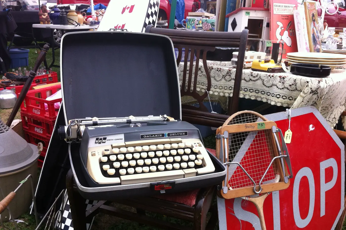 A vintage typewriter, a chair and household lots set out on tables at an outdoor sale