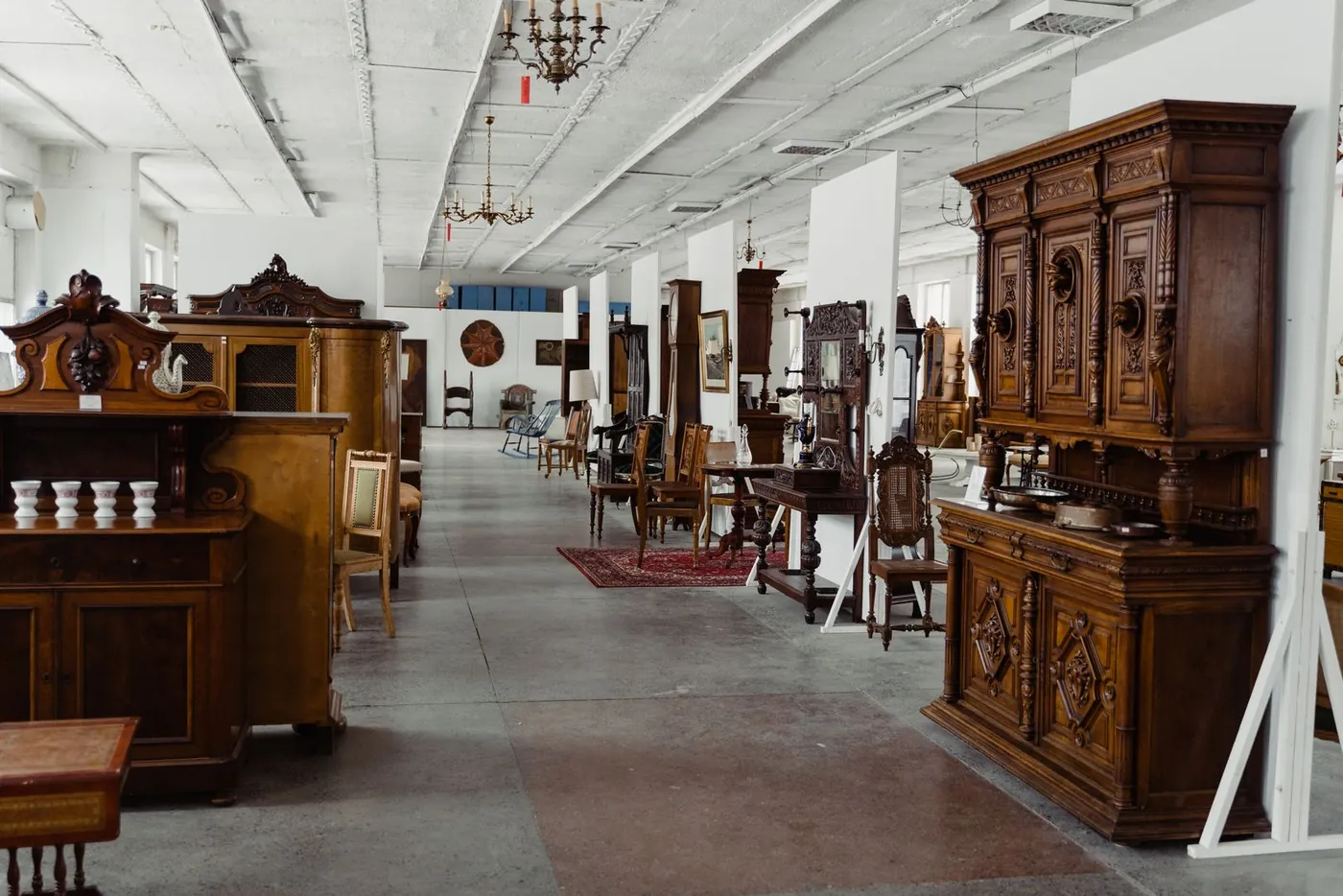 A long showroom of antique cabinets, chairs and chandeliers set out for viewing