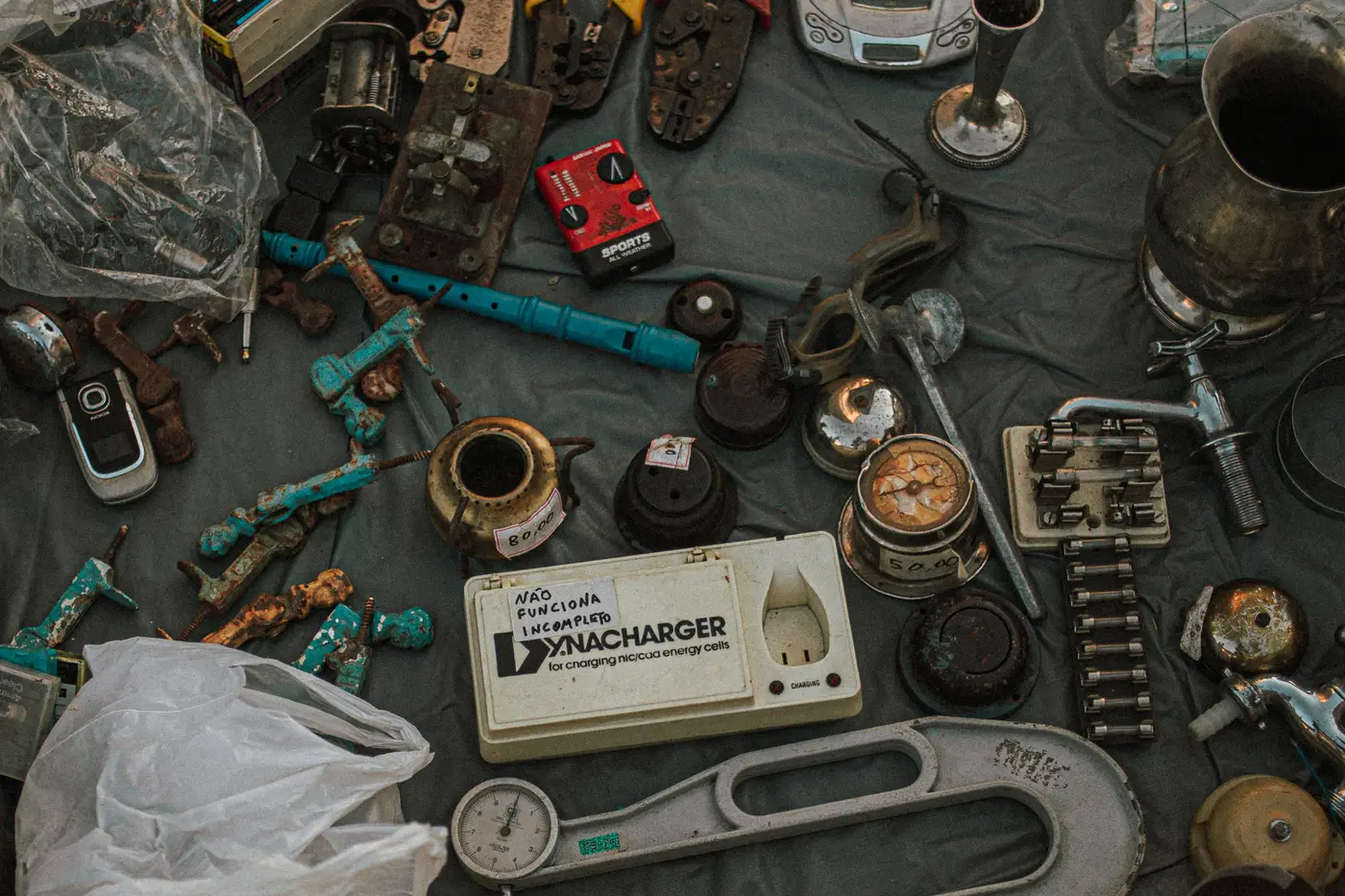 Old metal tools and household items laid out as lots at an outdoor sale