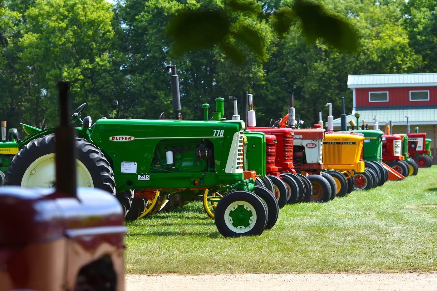 A row of vintage tractors lined up outdoors on a sunny day